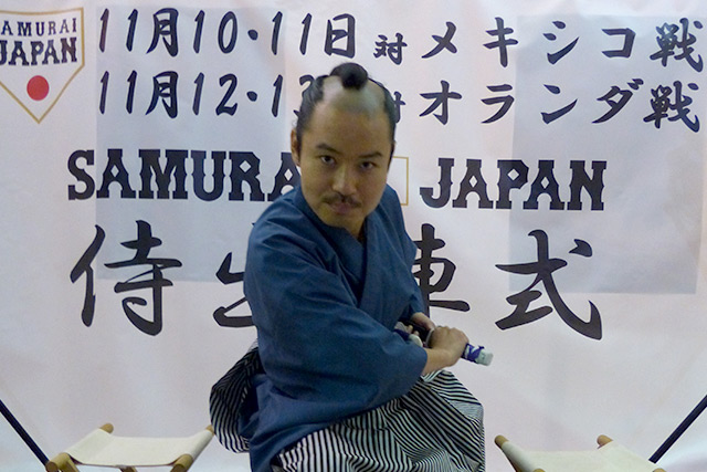 天幕の前で刀を構えるお笑いタレント・お侍ちゃん
