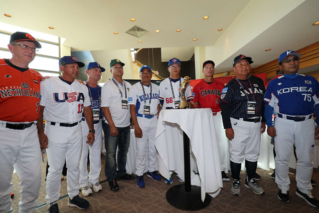 11チームの監督の中心には優勝トロフィー